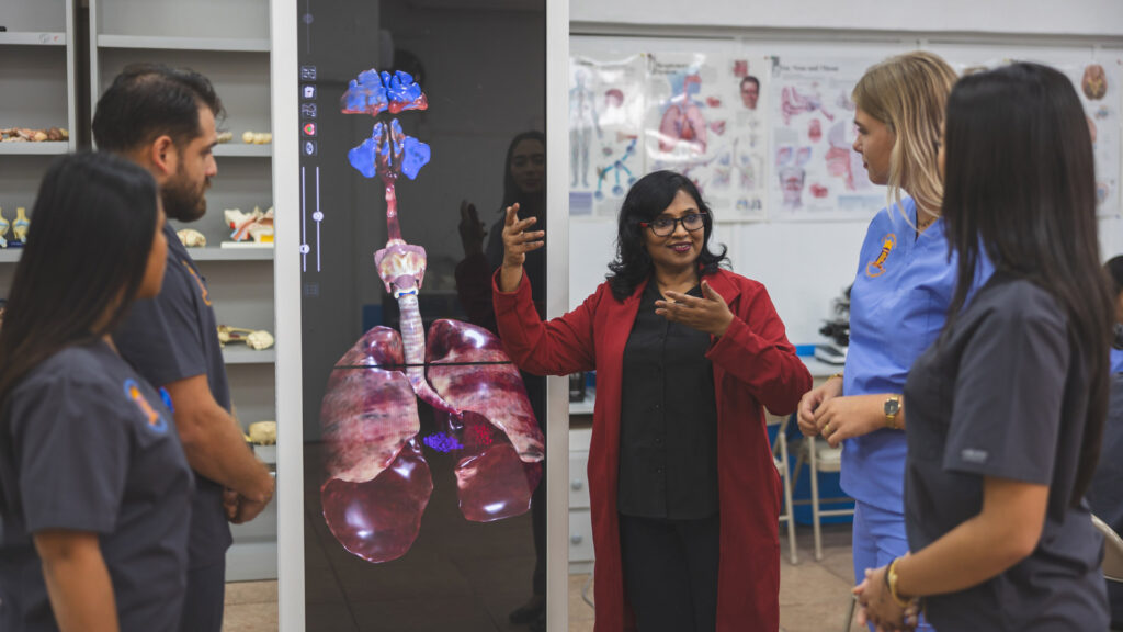 Teacher lecturing students, pointing at a digital image of internal organs