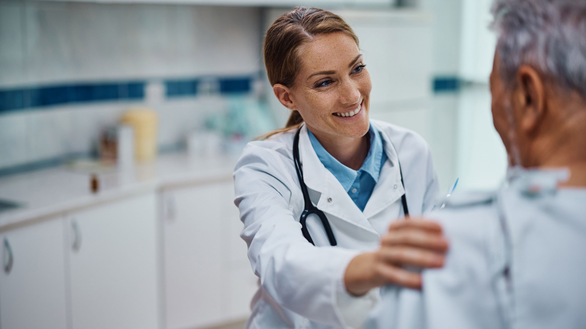 Doctor smiling, with hand on patient's shoulder
